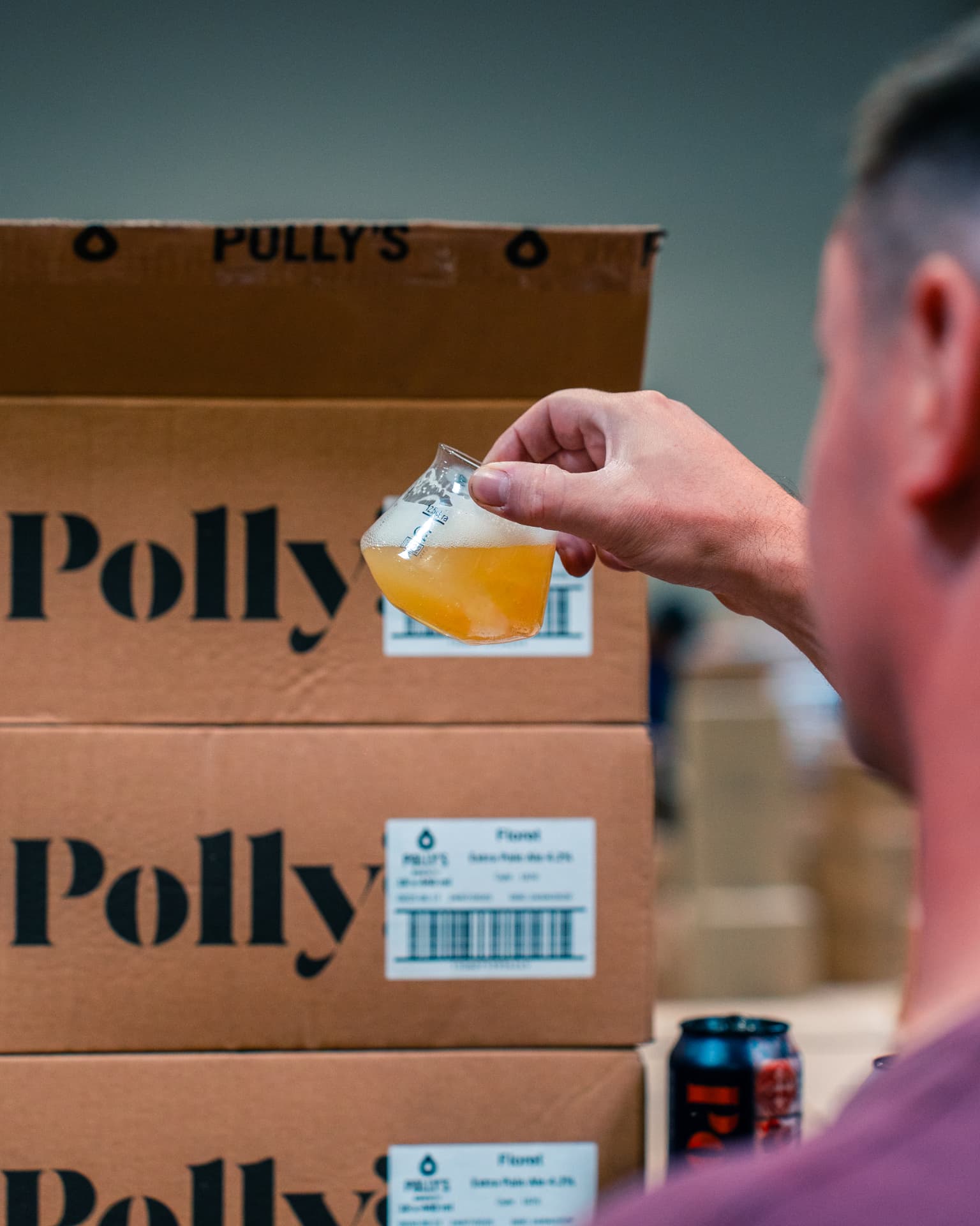 Verre de bière artisanale devant des cartons de brasserie